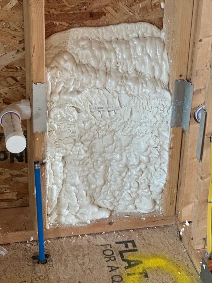 Close-up of spray foam packed into a wall cavity behind plumbing, Simsbury, CT