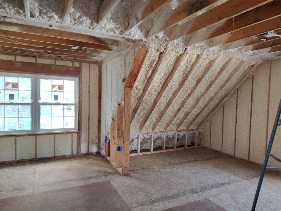 Foam sprayed between the sloped rafters and across the walls of an upper room, Madison, CT