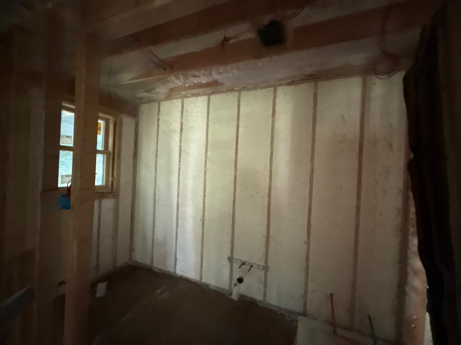 Spray foam filling the stud bays of an interior wall, New Castle, NY